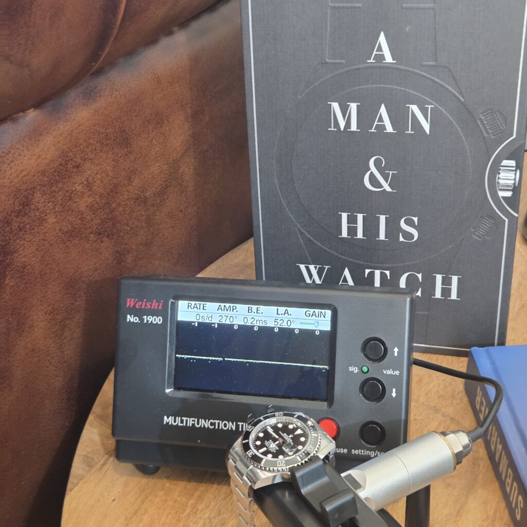 A Rolex Submariner clamped to the microphone of a Weishi 1900 timegrapher, the screen reading 0 seconds per day